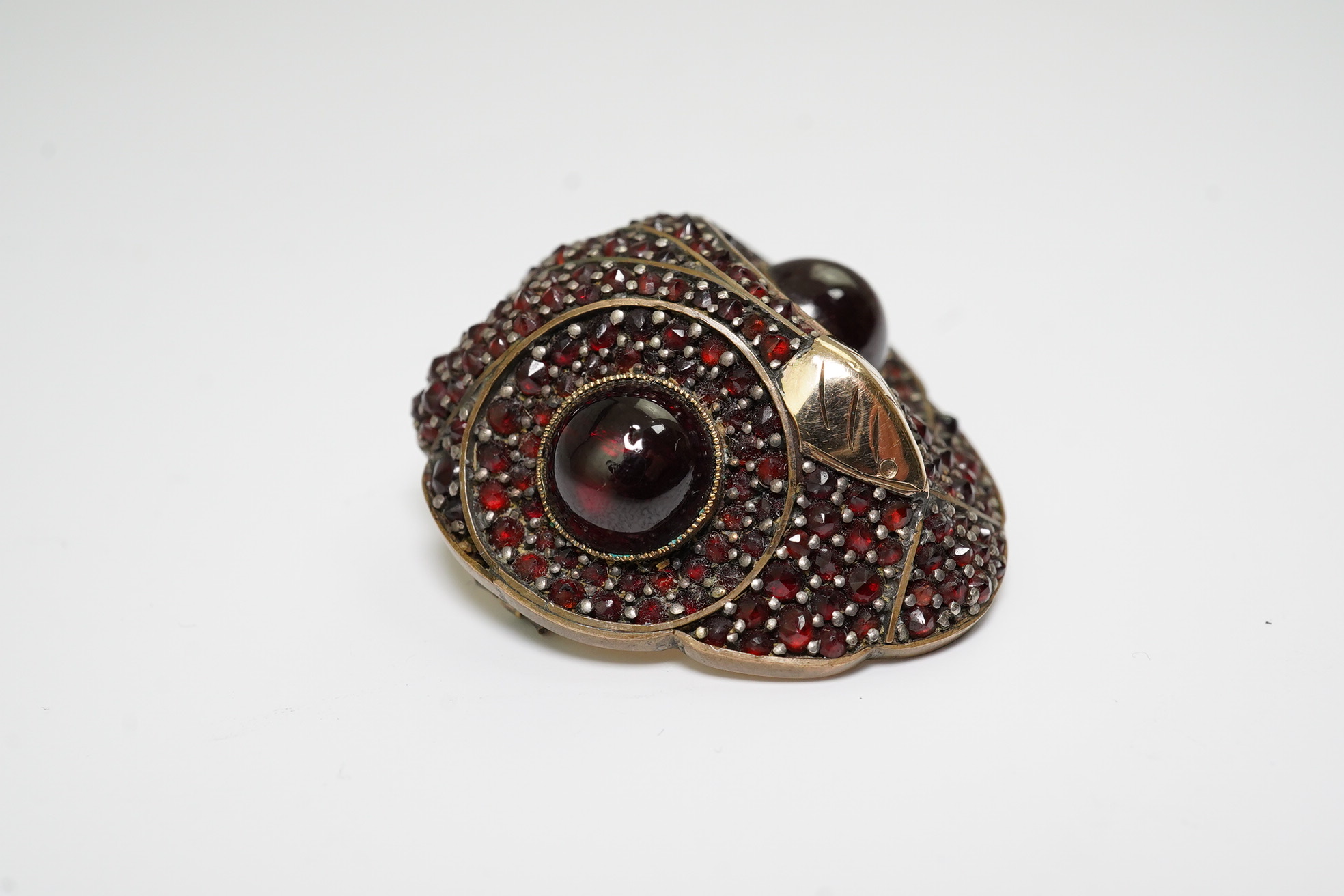 A Victorian gold overlaid base metal and pave set garnet owl's head brooch